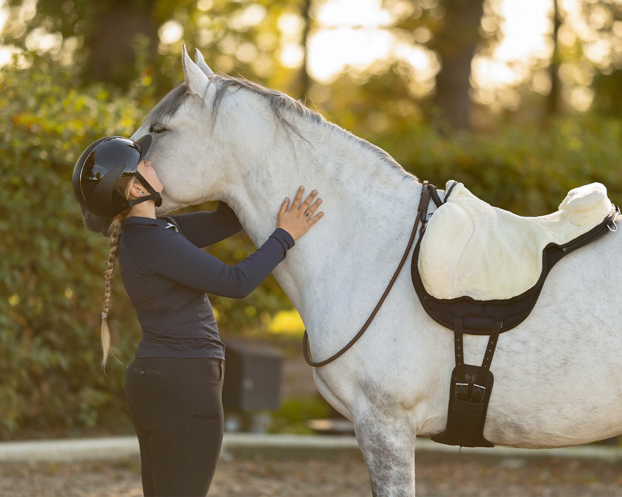 Woman hugging a horse that's wearing a bareback pad and bridleless neck rope